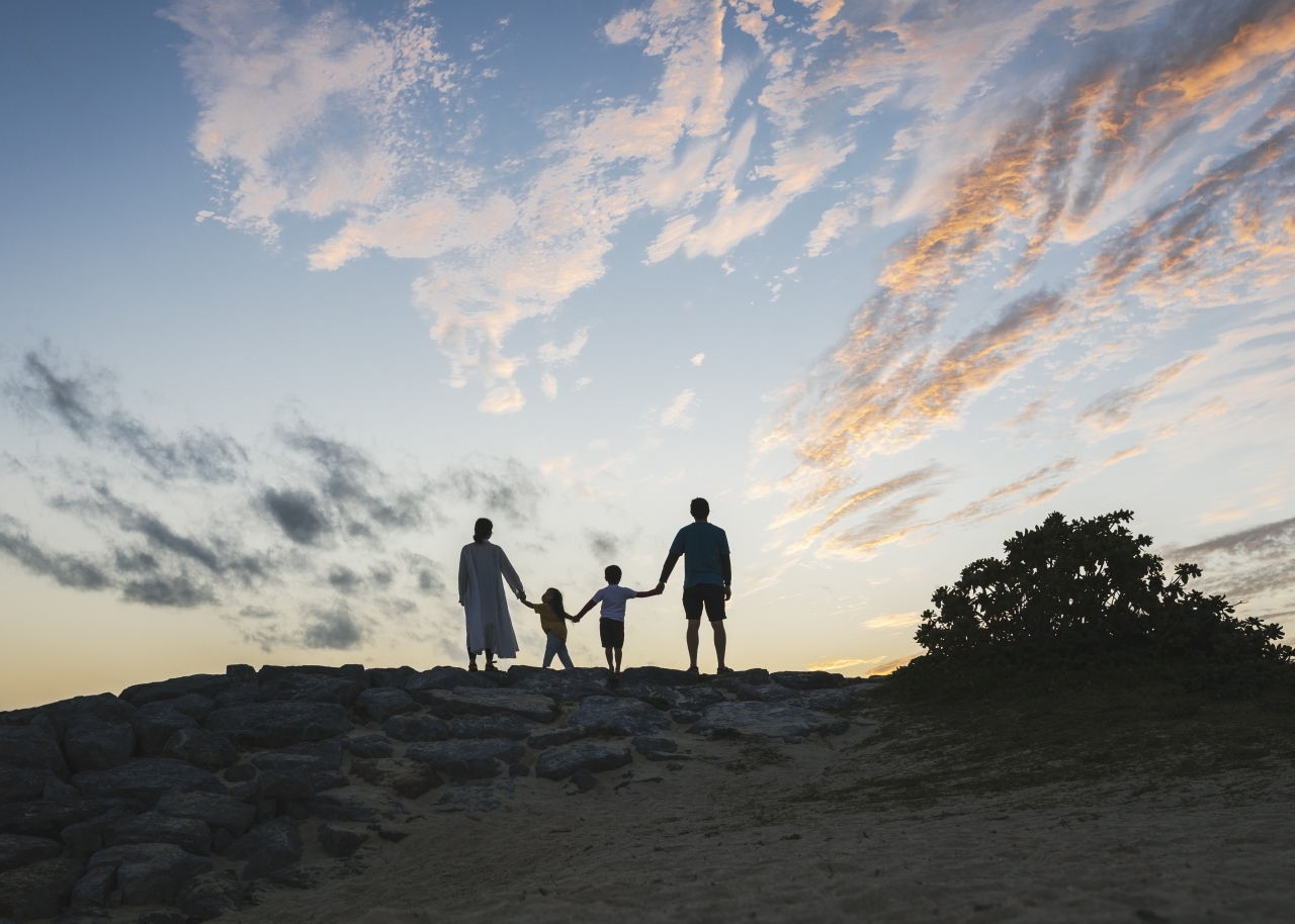 Asian father, mother, son and daughter playing in the beach in Okinawa at sunset.